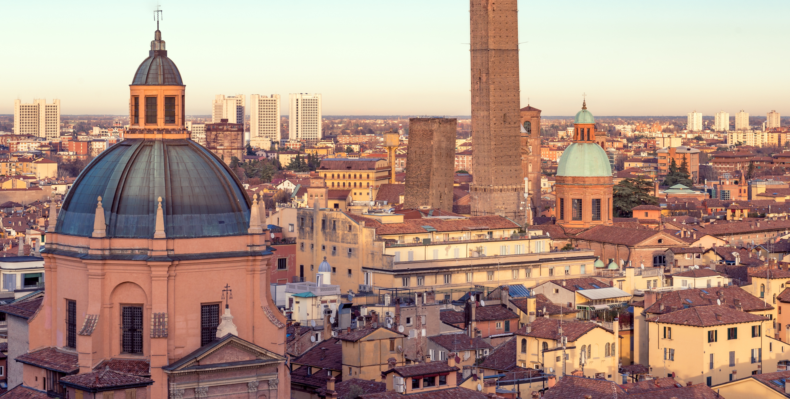 Vista panoramica di Bologna al tramonto con toni caldi.